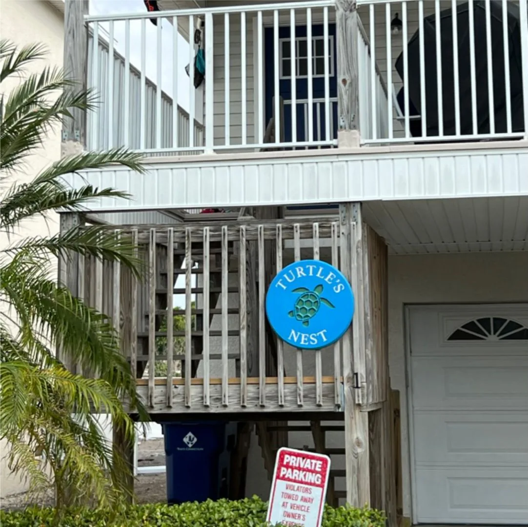Turtles Nest beach house sign on the stairs of a raised beach house