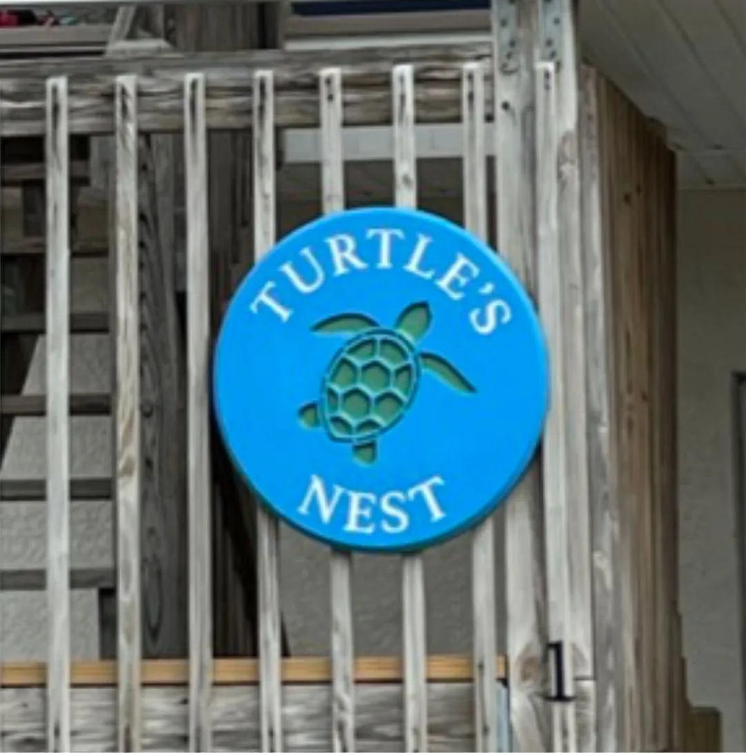 Turtles Nest round beach house sign in bright blue on a stair rail