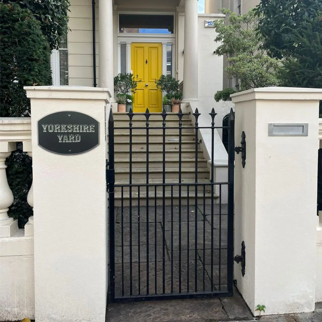 Charcoal Yorkshire Yard plaque on a white gate pillar with stairs to a yellow front door