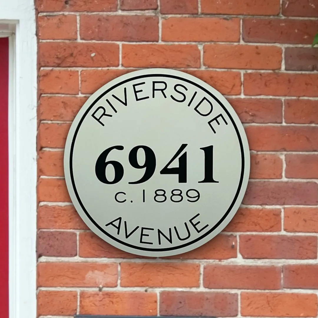 Round 6941 Riverside Avenue house sign on a brick wall