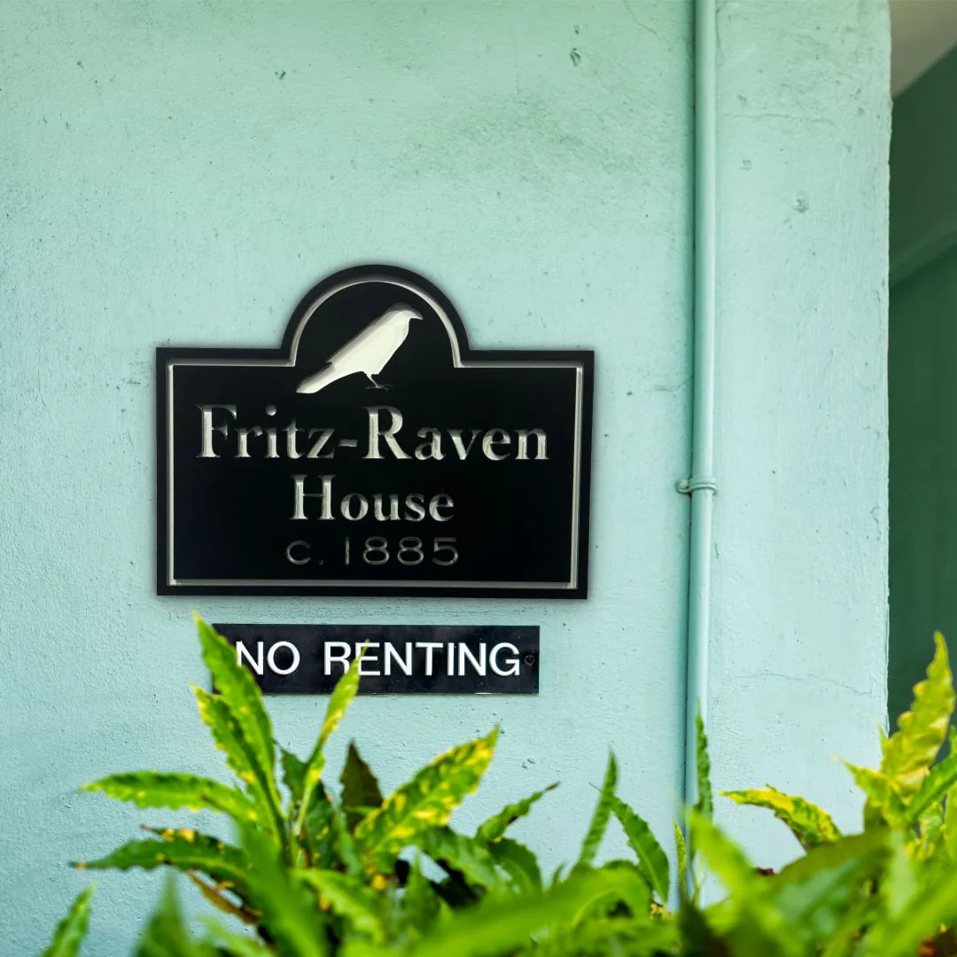 Black historic sign with a raven reading Fritz-Raven House c. 1885 on a mint green wall