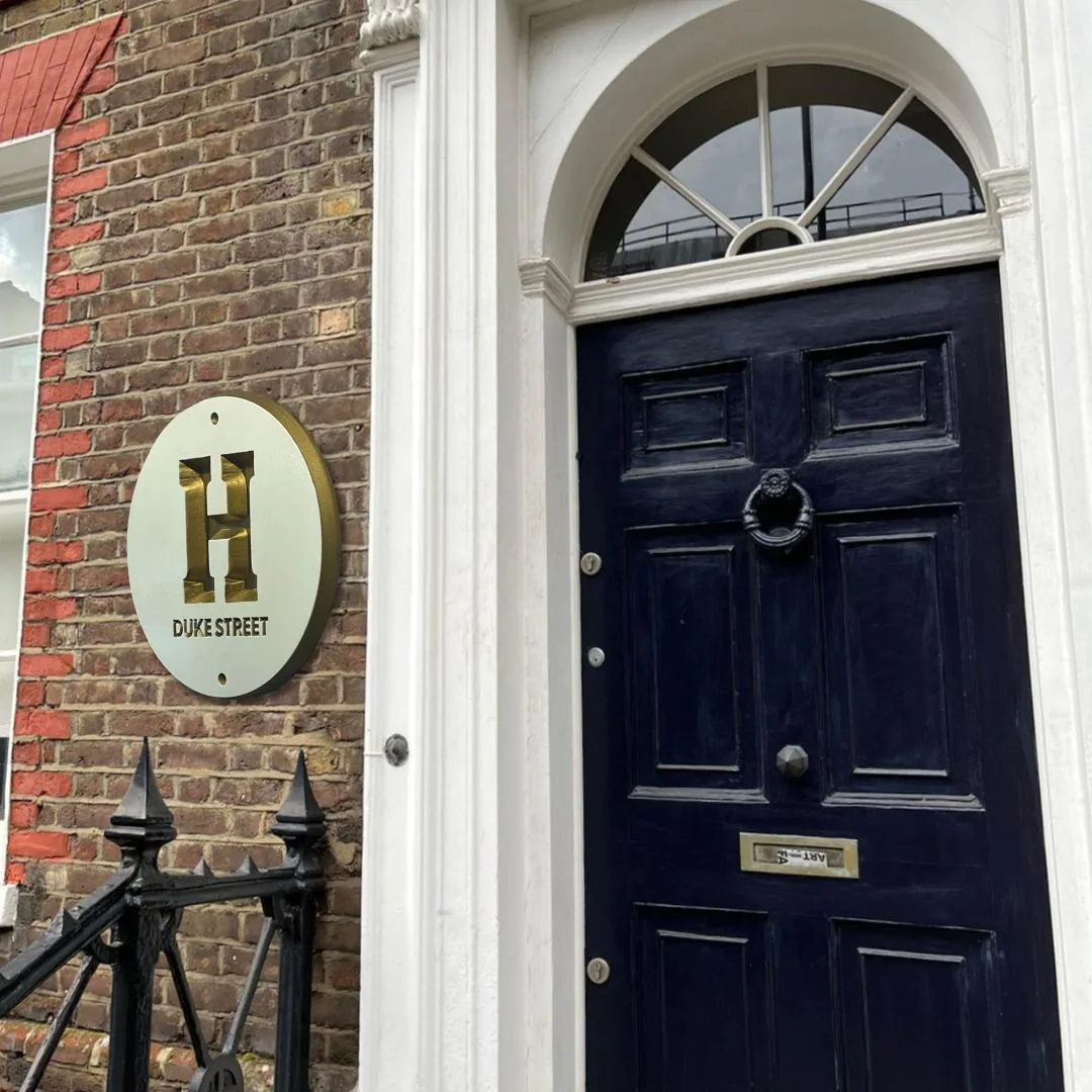 Round H Duke Street plaque on brick beside a white column