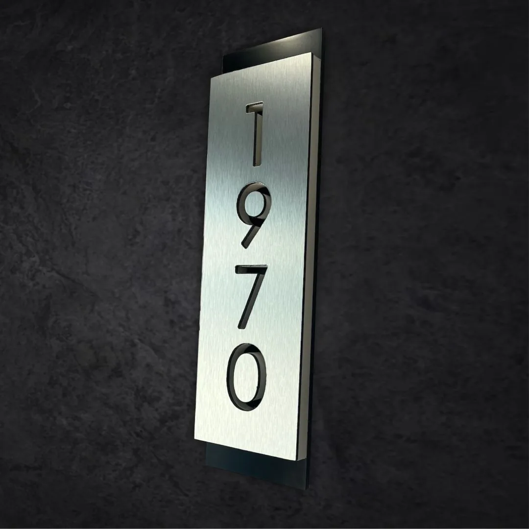 1970 vertical address numbers in brushed aluminum on a dark wall