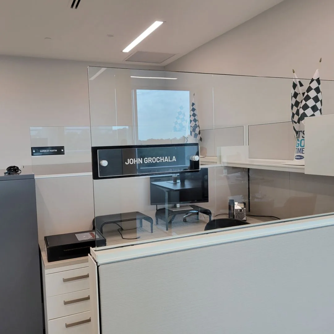 Acrylic name sign reading John Grochala mounted on a glass office wall