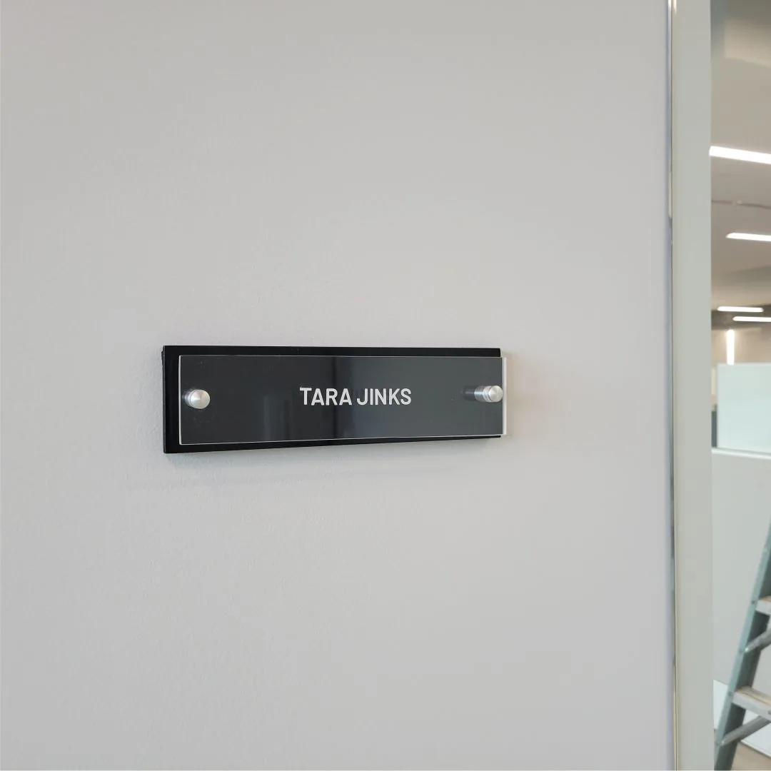 Acrylic office name sign reading Tara Jinks on a white wall