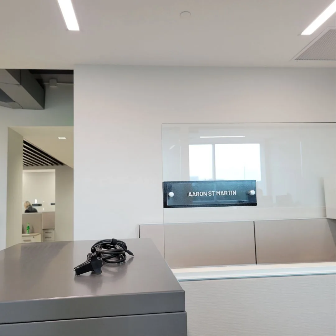 Acrylic name sign on a glass office front beside an open workspace