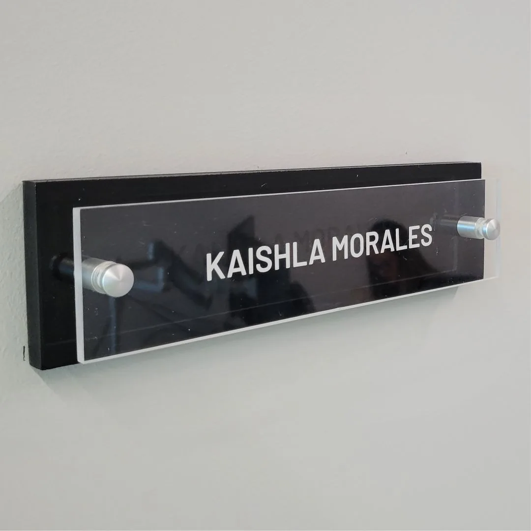 Black and clear acrylic office name sign reading Kaishla Morales on brushed aluminum standoffs