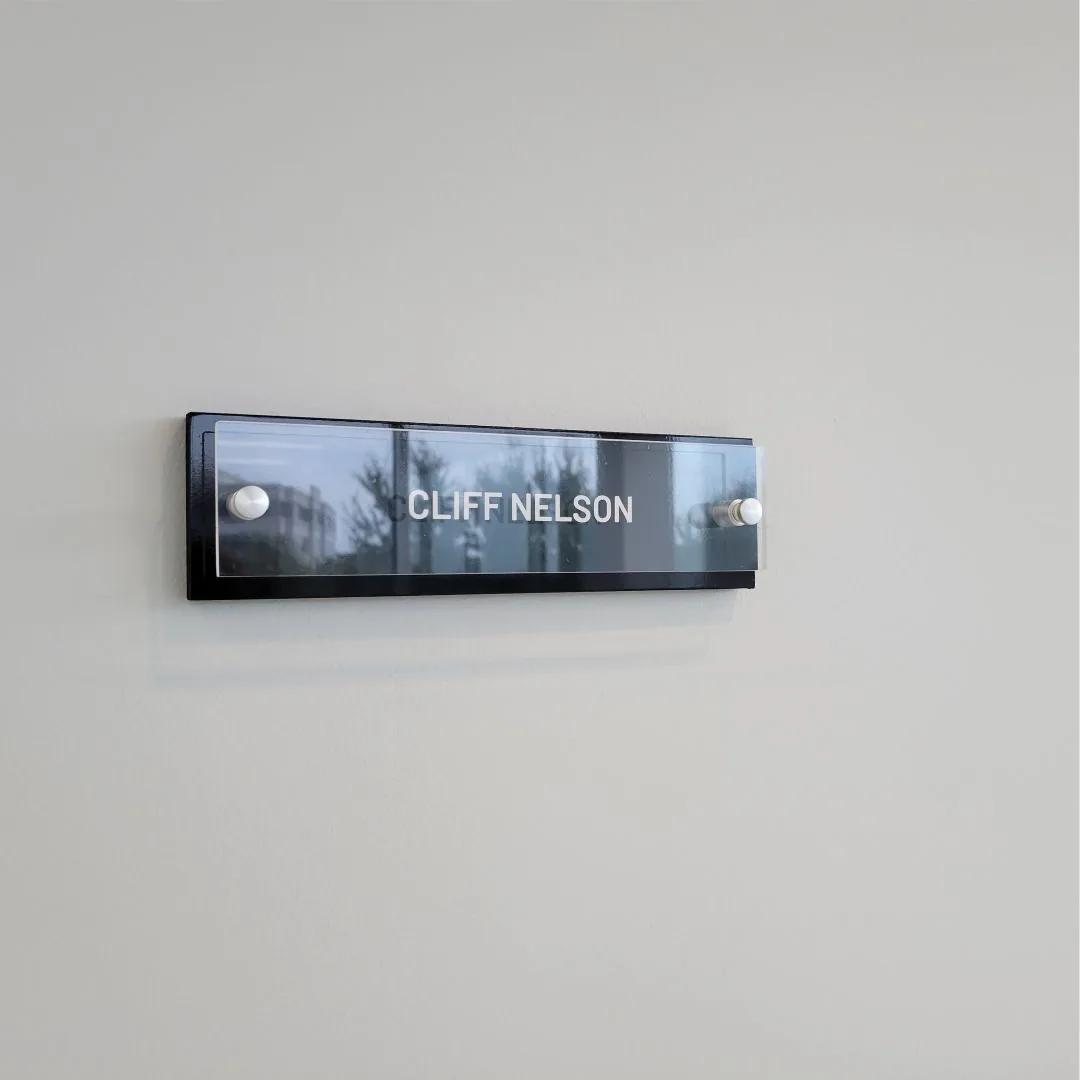 Acrylic office name sign reading Cliff Nelson on a white wall