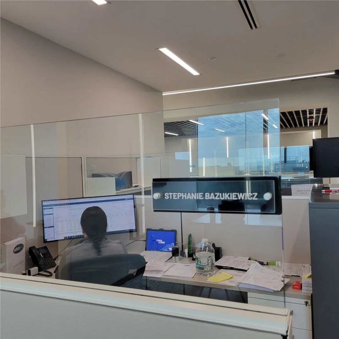 Acrylic name sign on a glass partition above an office workstation