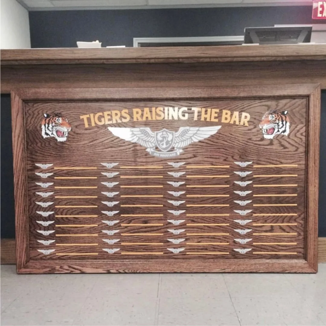Wood Tigers Raising the Bar board with a squadron emblem and rows of name plates